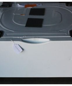 A white appliance pedestal drawer viewed from the front, with black rectangular pads placed on the top surface and a small white label tagged on the left side. The outer surface is smooth and clean, while the handle is centered on the front panel.